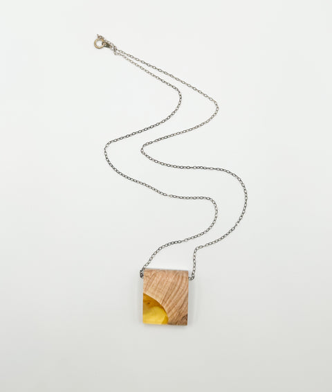 A handmade necklace with a resin pendant and a wooden chain.