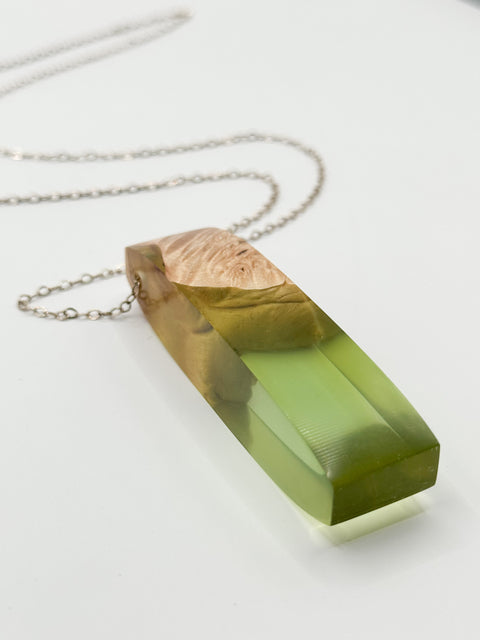A sterling silver necklace with a large teardrop-shaped pendant made of wood and resin, displayed against a white background.