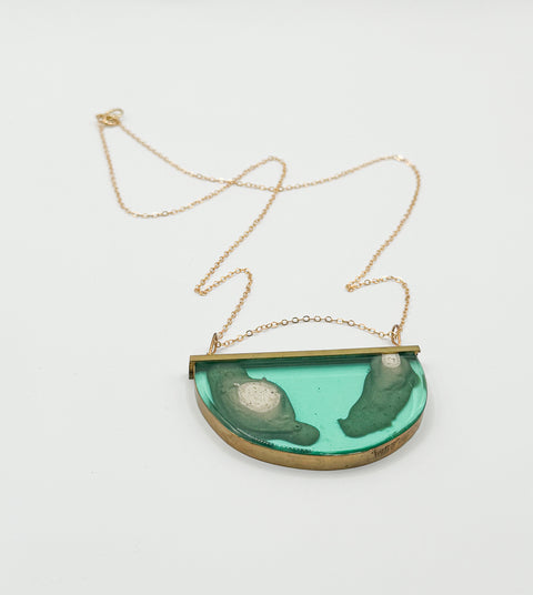 A green and gold necklace with a resin pendant designed by Rosa Murillo.