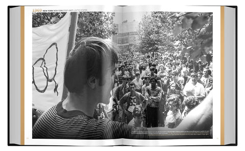 Open book showing a black and white photograph of a person with a banner in a crowd.