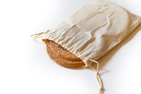 Beige drawstring bag with two coasters on a white background
