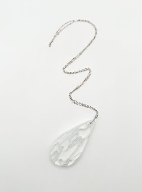 A silver-colored necklace with a teardrop-shaped resin pendant featuring a wave-like pattern, attached to a chain.