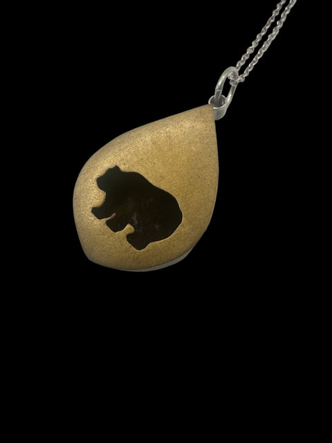 A gold-colored bear-shaped shadowbox pendant.