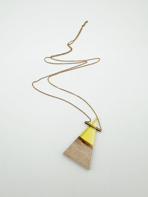 A wooden triangle-shaped pendant with a gold-colored metal chain and a resin tube necklace.