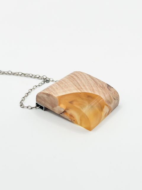A handmade necklace with a resin pendant and a wooden chain.