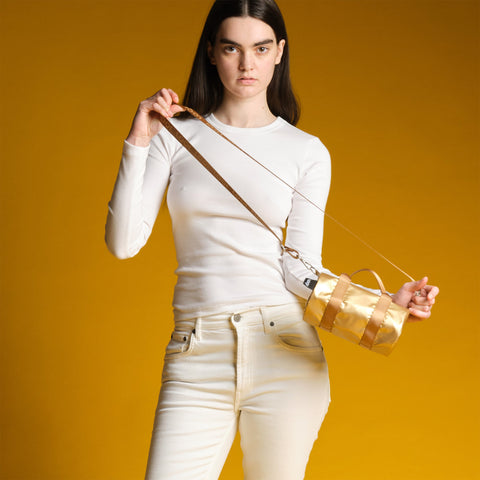 Woman holding a gold handbag against a yellow background
