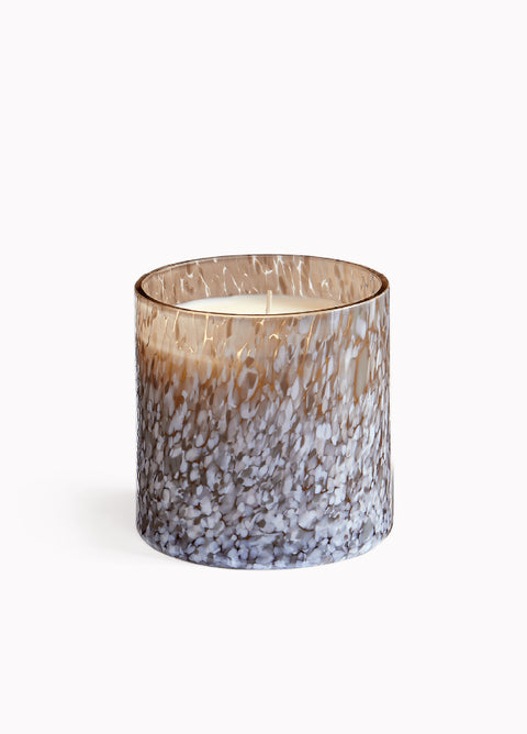 Candle in a decorative glass container on a white background