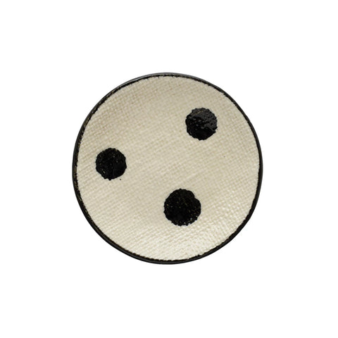 A round hand-painted stoneware dish with a black and cream color, featuring dots and a linen texture.