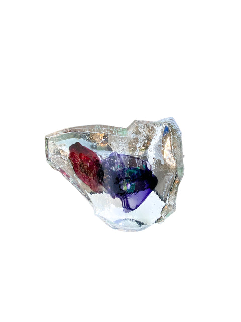 A hot cast glass sculpture with a heart-like shape, featuring layers of purple and red colors, and an inscription on the surface.