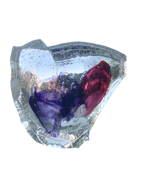 A hot cast glass sculpture with a heart-like shape, featuring layers of purple and red colors, and an inscription on the surface.