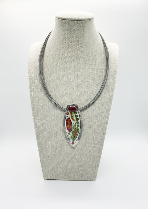 A necklace with a large pointed enamel carnelian pendant displayed on a mannequin bust.