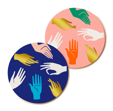 Two coasters, one pink, one blue, with printed hands doing Hamsa signs.