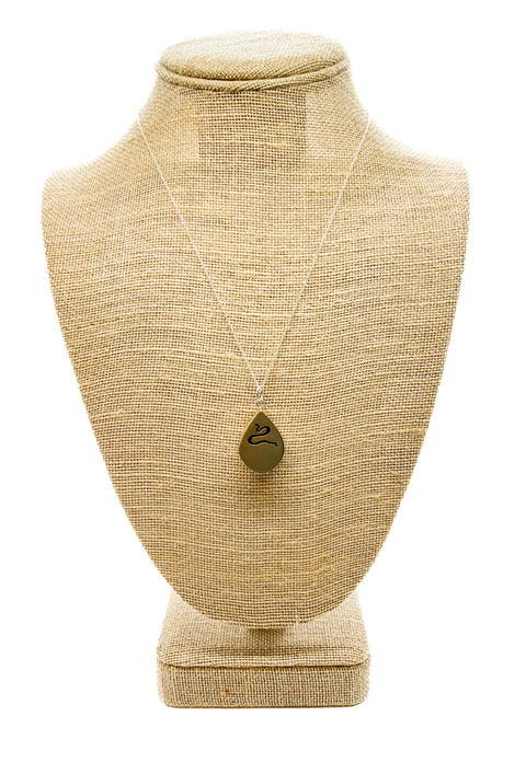 A handcrafted silver pendant in the shape of a snake silhouette displayed on a mannequin bust.