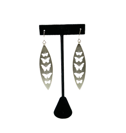 A pair of earrings featuring hand-cut butterfly silhouettes, with silver earwire and a black hook.
