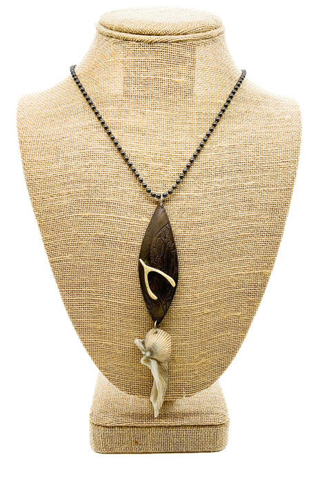 A wishbone pendant necklace displayed on a mannequin bust. The pendant is made of wood with a bone wishbone detail, and different objects, and the necklace chain is black.