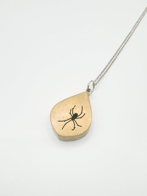 The spider silhouette in this pendant is hand-cut from sheet brass using a jeweler's saw, then fabricated into a lightweight shadow box.