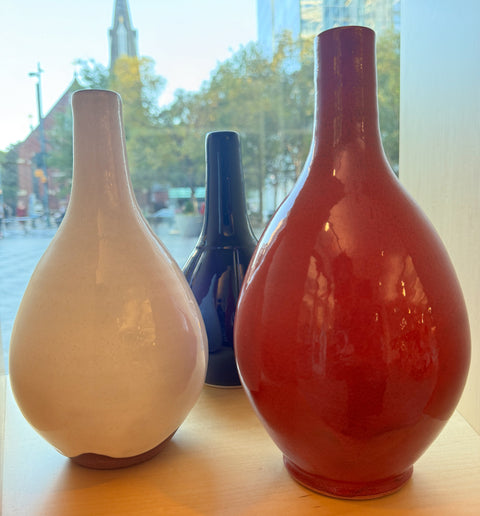 Three different pottery vases, (left to right: white, blue, and red vases).