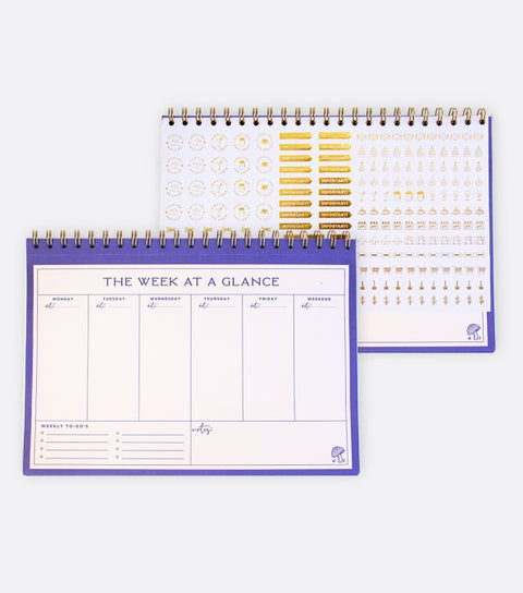 A purple and beige hardcover weekly desk planner.