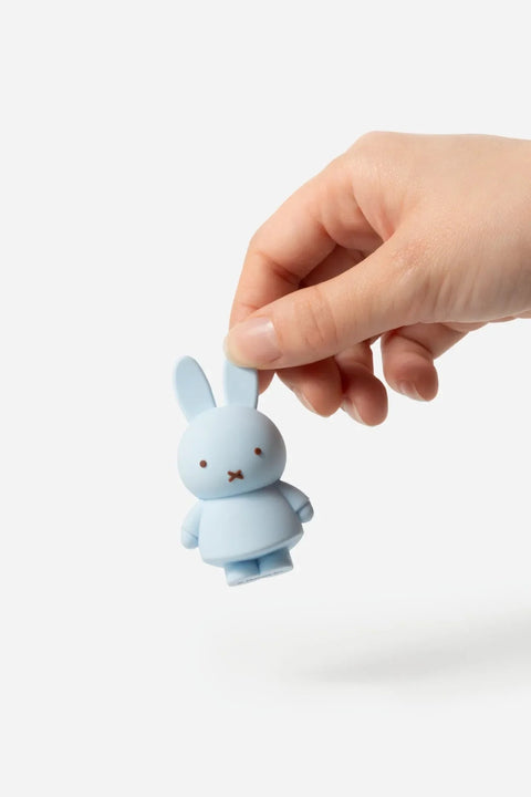 Hand holding a small blue rabbit figurine against a white background