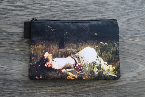 Pouch with a printed design of a person lying on grass on a wooden surface