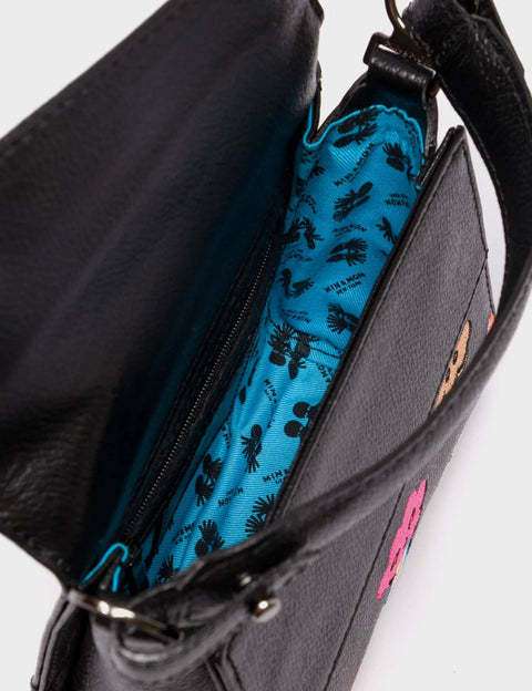 Black handbag with blue interior lining featuring black floral patterns on a white background