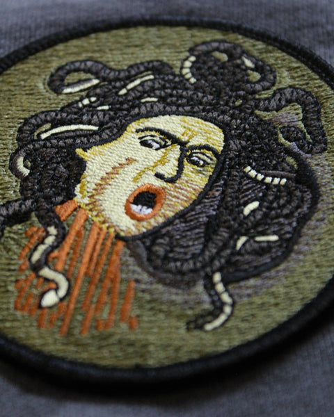 Embroidered patch of Medusa on a textured fabric background