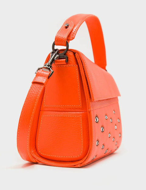 Orange handbag with studded details on a light gray background