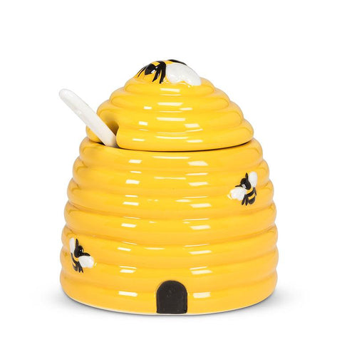 Yellow ceramic beehive with bee designs on a white background