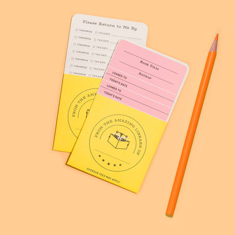 Two colorful library card holders with an orange pencil on a peach background