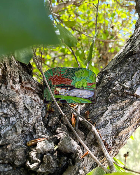 Colorful nature-themed pin on a tree trunk