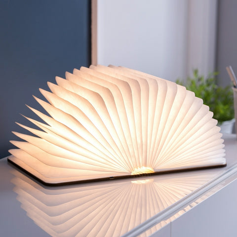 Book-shaped lamp on a reflective surface with a blurred indoor background