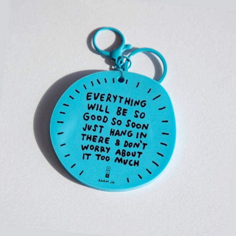 Blue keychain with motivational quote on a light gray background