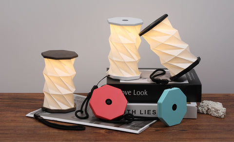 Three spool-shaped lamps on a wooden surface with a book underneath.