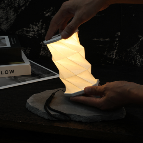 Foldable lamp being held by a person in a dark setting