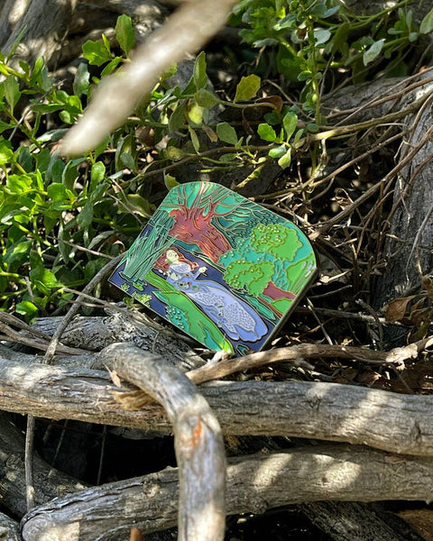 Colorful nature-themed pocket mirror on a wooden surface with greenery