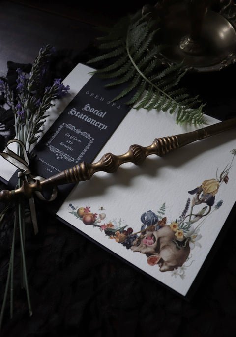 Stationery set with a pen, card, and decorative elements on a dark surface