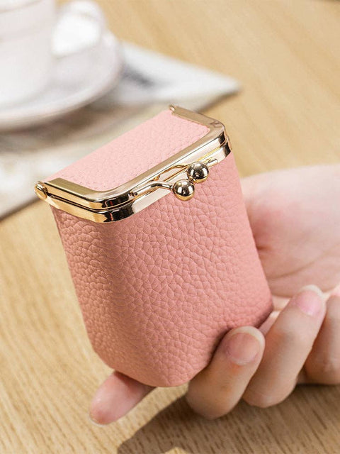 Pink leather clutch held by a hand on a wooden surface