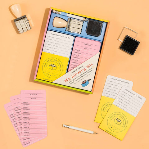 Library-themed stationery set with cards, stamp, and ink pad on a peach background