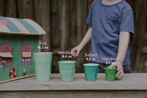 Child playing with green cups of different sizes outdoors