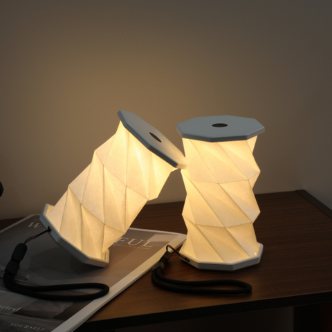 Origami-style lamp on a table with a magazine underneath