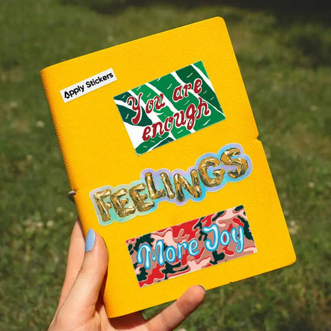 Yellow notebook with motivational stickers on a grassy background