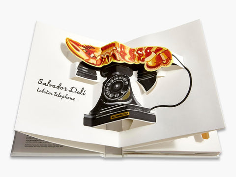 Open book with a Salvador Dali 'Lobster Telephone' illustration on a white background