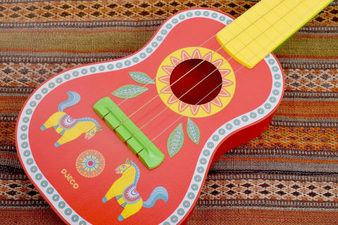 Children's wooden ukulele with colorful animal artwork on the body in a fabric background