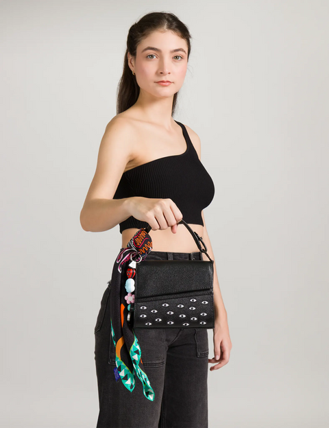 Woman wearing a black crop top and black pants with a colorful belt bag on a light gray background