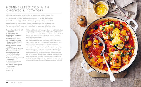 Dish of home-salted cod with chorizo and potatoes on a wooden board with the recipe on the left.