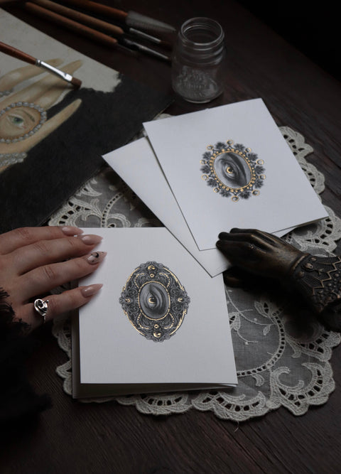 Artistic designs on paper with hands and stationery items on a lace doily.