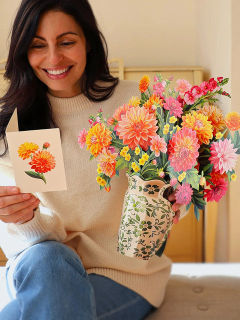 Woman holding a bouquet of flowers and a card with floral design.