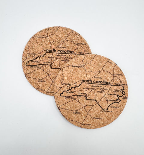 Two cork coasters with a map of North Carolina on a white background