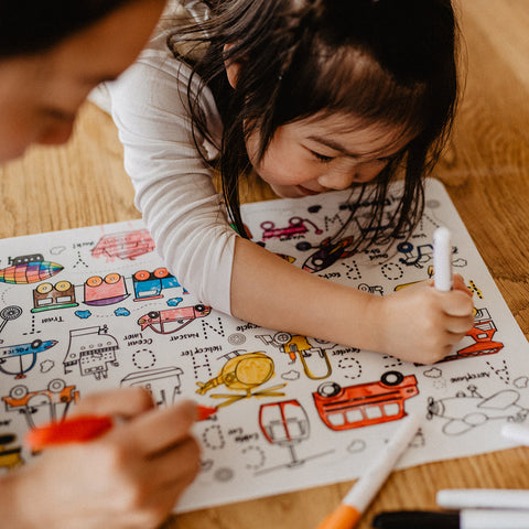Child coloring on a paper with adult supervision