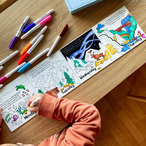 Coloring book with a child's hand using markers on a wooden table